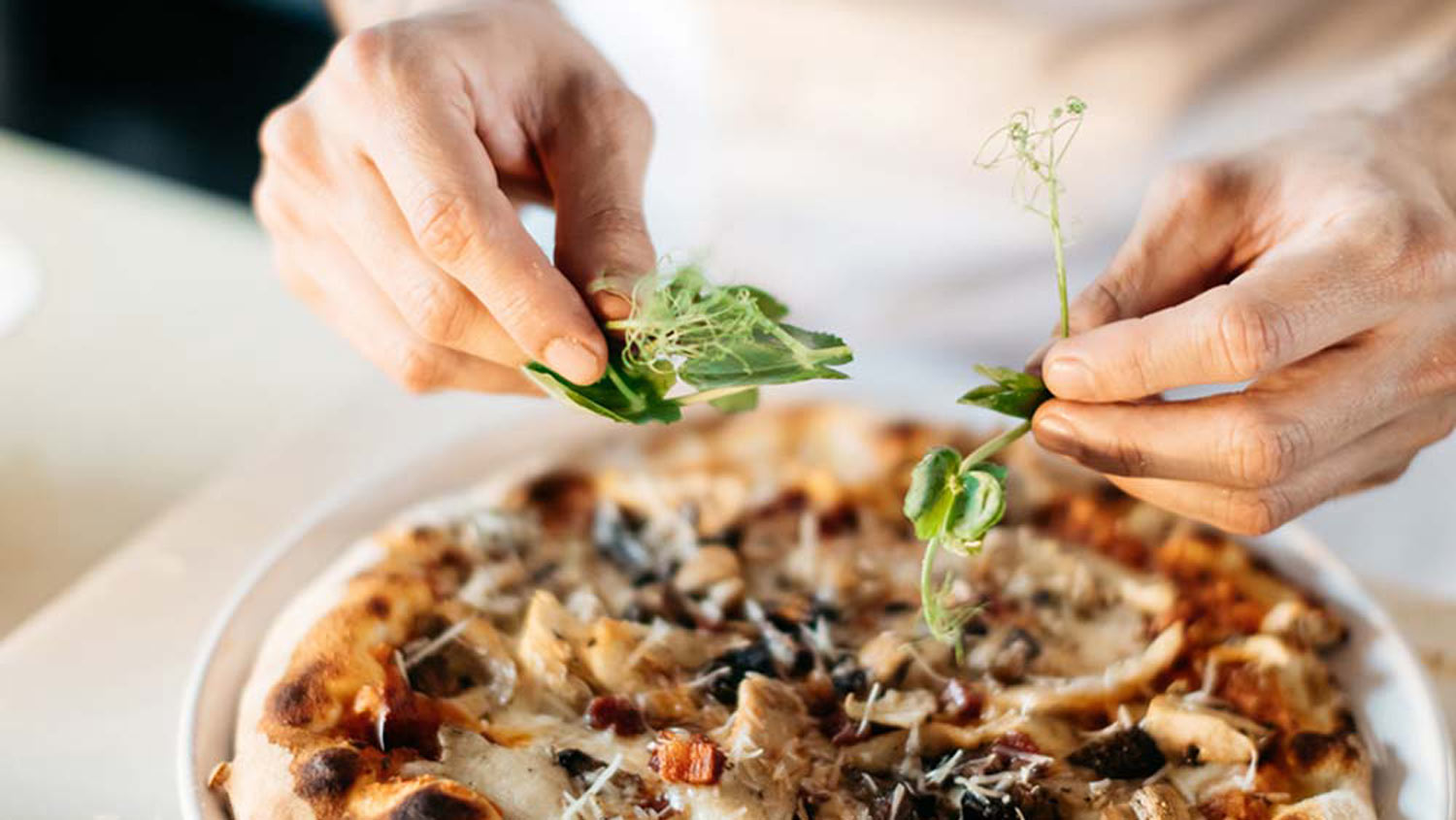En person garnerar en pizza